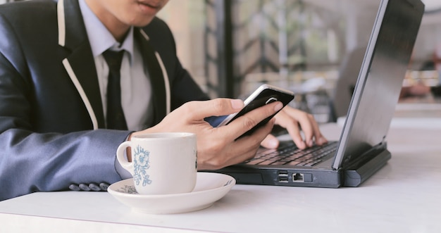 Een man draagt een masker terwijl hij een laptop gebruikt voor zijn werk