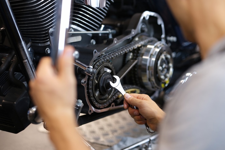 Foto een man draait een onderdeel van een motorfiets met een moersleutel