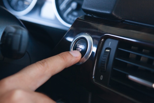 Een man drukt op de startknop in de auto