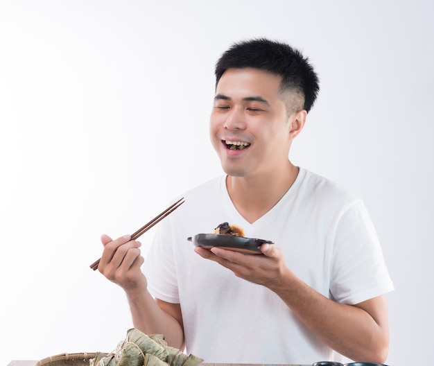 Een man eet heerlijke zongzi (rijstbol) en voelt zich heerlijk op Dragon Boat Festival, Aziatische traditionele gerechten, witte achtergrond