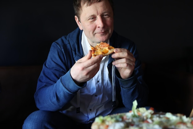 Een man eet pizza in een café