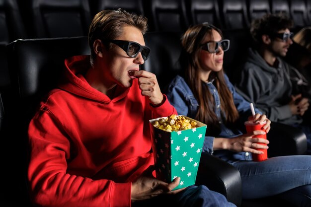 Een man eet popcorn en kijkt naar een 3D-film in de bioscoop