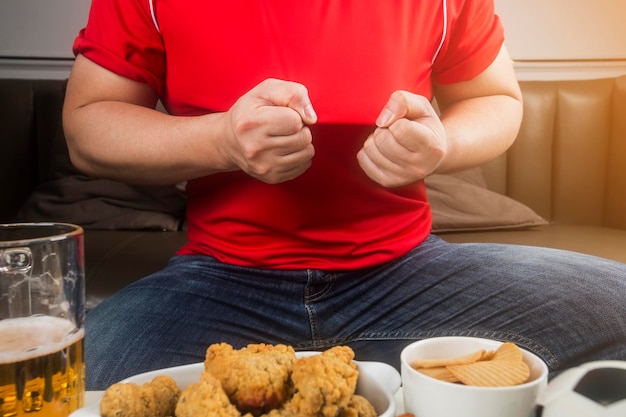 Een man eet snacks en drinkt bier thuis