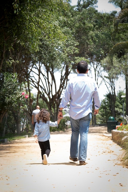 Foto een man en een kind lopen langs een pad met bomen op de achtergrond