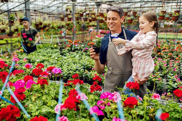 een man en een klein meisje houden planten in een kas