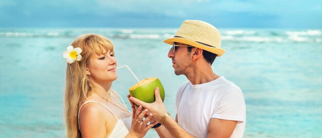 Een man en een meisje op het strand drinken kokos