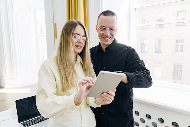 Een man en een vrouw die allebei een bril dragen, kijken naar inhoud op een tablet en delen een moment