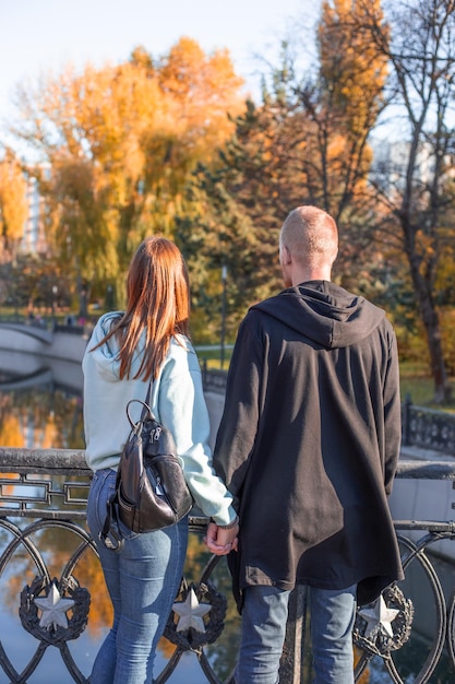 Een man en een vrouw houden elkaars hand vast op een brug in een herfstpark Romantisch weekendje weg