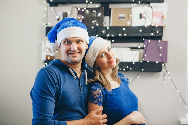 Een man en een vrouw in kerstmutsen omhelzen elkaar.