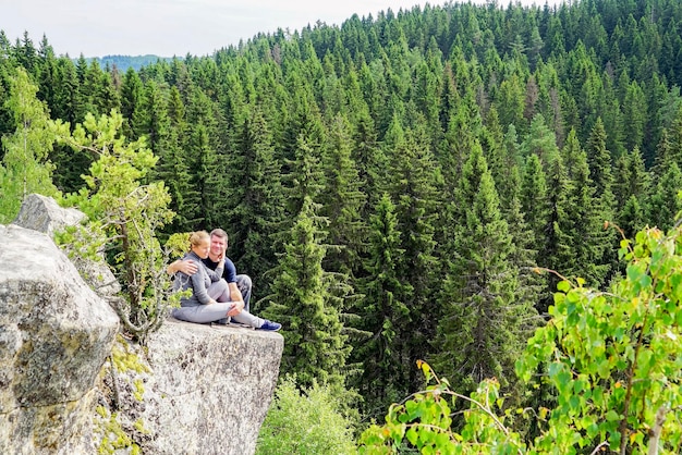 Een man en een vrouw knuffelen elkaar aan de rand van een berg in de natuur