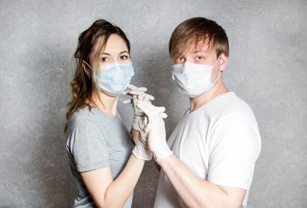 Een man en een vrouw met rubberen handschoenen en medische maskers houden elkaars hand vast. OKVED-19