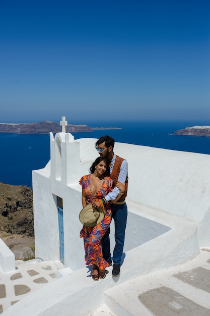 Een man en een vrouw omhelzen elkaar tegen de achtergrond van Skaros Rock op het eiland Santorini. Het dorp Imerovigli. Hij is een etnische zigeuner. Ze is een Israëlische.