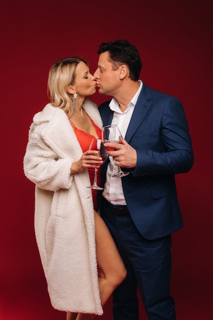 Een man en een vrouw verliefd op een glas champagne op een rode kus als achtergrond.