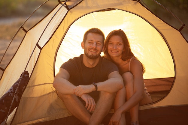 Een man en een vrouw zitten in een tent bij zonsondergang. Huwelijksreis tijdens de wandeling