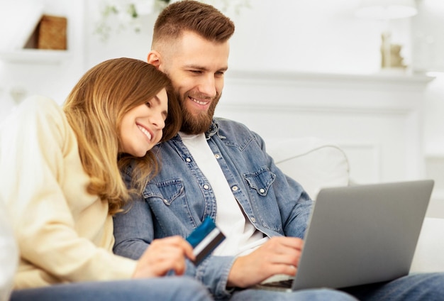 Een man en een vrouw zitten op een bank gericht op een laptop scherm voor hen