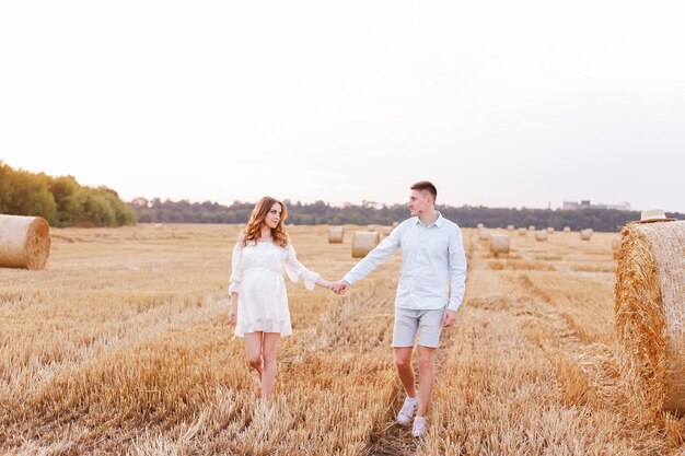 Een man en zijn geliefde vrouw lopen bij zonsondergang hand in hand door een tarweveld