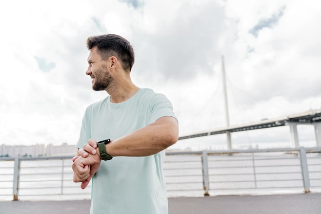 Een man gebruikt een fitnesshorloge om de tijd te meten dat een sportatleet zich opwarmt