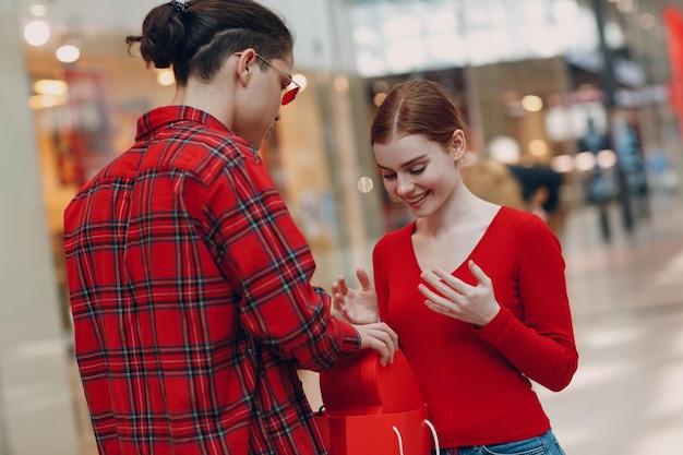 Een man geeft zijn vriendin een hartvormige doos op Valentijnsdag Jong stel in winkelcentrum