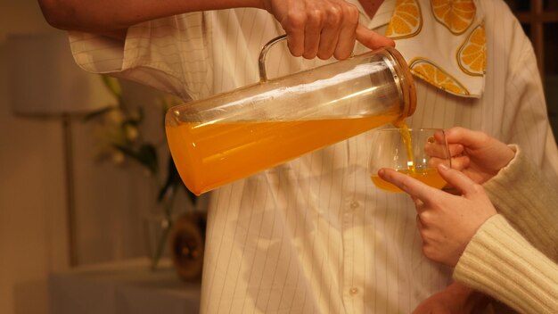 Een man giet sinaasappelsap in een glas