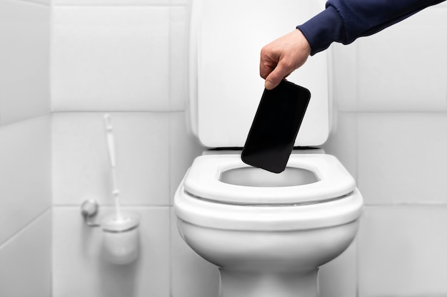 Een man gooit een mobiele telefoon smartphone in het toilet met zijn hand bevrijding van sociale afhankelijkheid...