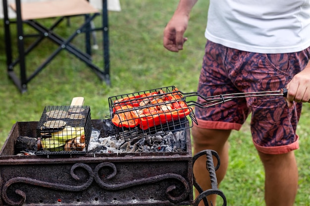 Een man grilt buiten groenten op een barbecue