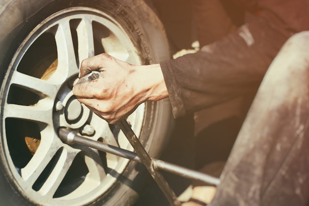 Foto een man haalt de moeren aan met een wielsleutel op het autowiel.