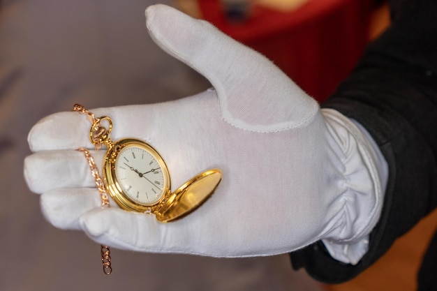 Een man heeft een gouden zakhorloge in zijn hand.