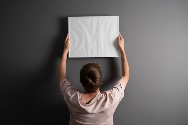 Een man houdt de blanco foto thuis vast en hangt hem aan de muur