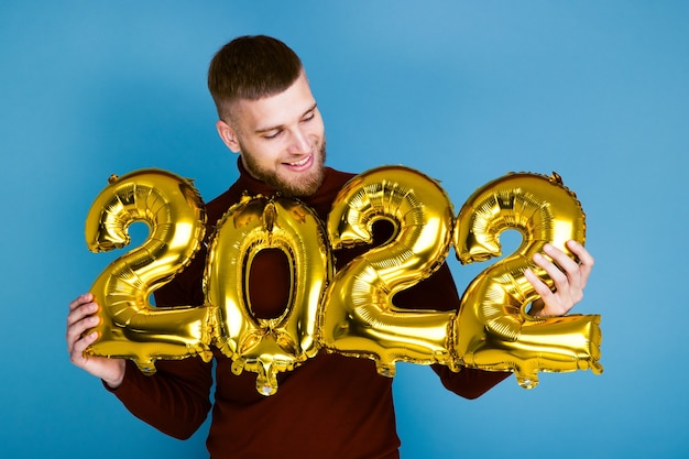 Een man houdt de nummers 2022 vast van gouden ballonnen. Het komende nieuwe jaar