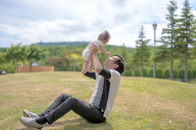 Een man houdt een baby in de lucht, de man houdt hem in de lucht.