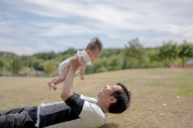 Een man houdt een baby in de lucht, met het woord liefde op de voorkant van zijn gezicht.