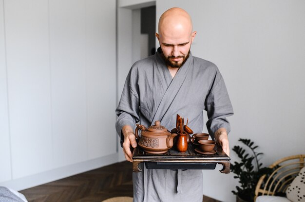 Een man houdt een dienblad met een servies vast voor een chinese theeceremonie.