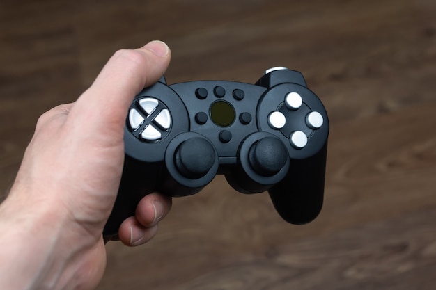 Een man houdt een draadloze gamepad van een videogameconsole in zijn hand