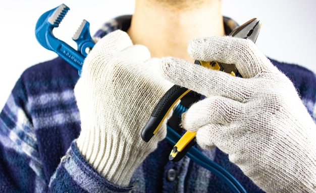 Een man houdt een moersleutel en een tang in zijn hand Een slotenmaker in handschoenen is klaar om te beginnen met het repareren van een pijp ter vervanging van een kraan sanitair werk