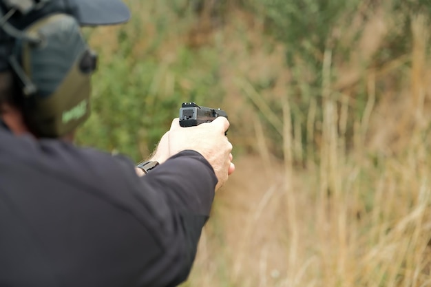 Foto een man houdt een pistool in zijn handen pistoolschietoefeningen