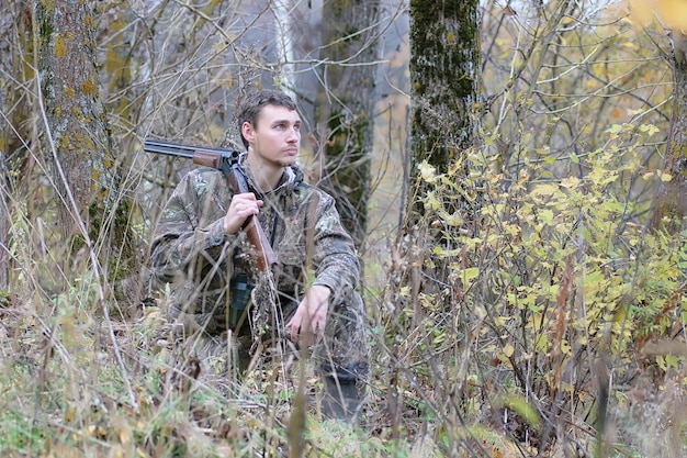 Een man in camouflage en met geweren in een bosgordel op een lentejacht