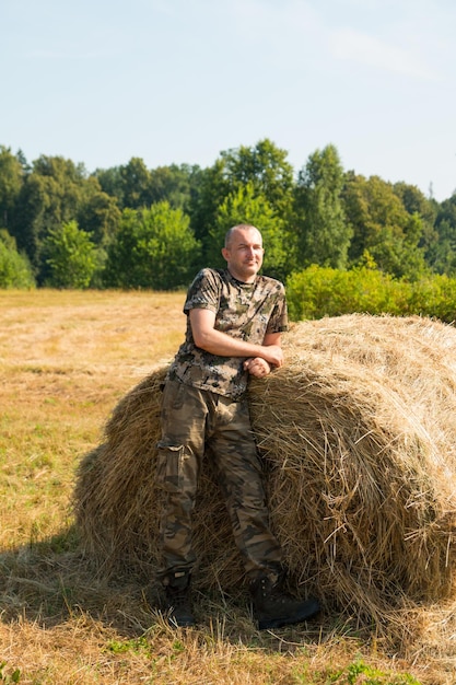 Een man in de buurt van een hooiberg in militaire kleding Vroege zomerochtend in het veld