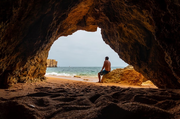 Een man in de natuurlijke grot in de Algarve op het strand van Praia da Coelha Albufeira Portugal