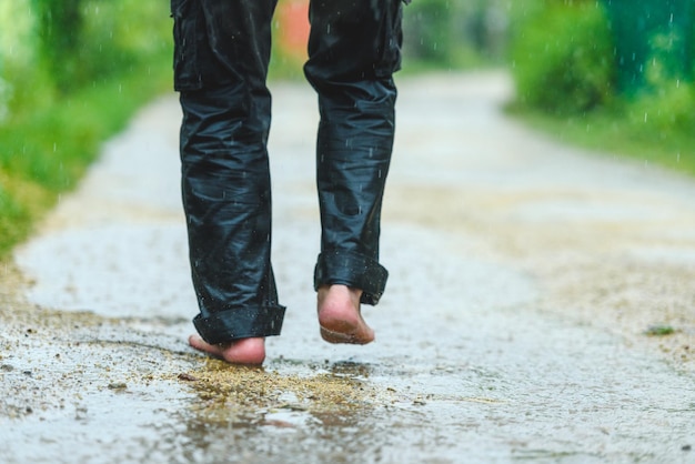 Een man in de regen is blootsvoets in plassen