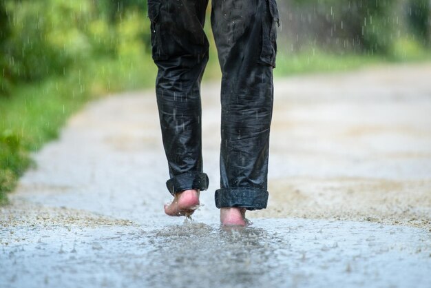 Een man in de regen is blootsvoets in plassen