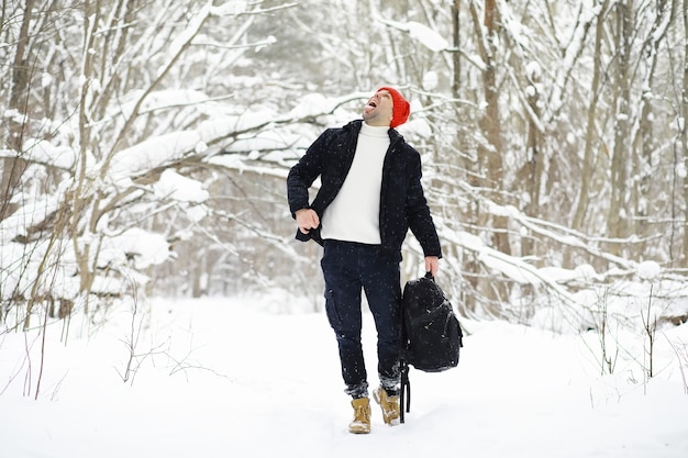 Een man in de winter in het bos. Een toerist met een rugzak gaat in de winter door het bos. Winterse beklimming.