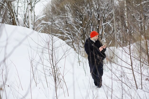 Een man in de winter in het bos. Een toerist met een rugzak gaat in de winter door het bos. Winterse beklimming.
