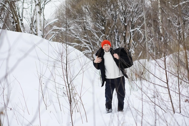 Een man in de winter in het bos. Een toerist met een rugzak gaat in de winter door het bos. Winterse beklimming.