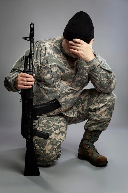 Een man in een Amerikaans camouflage-uniform en legerlaarzen met een Kalashnikov-aanvalsgeweer in zijn hand...