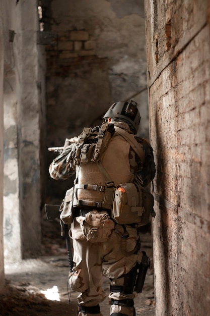 een man in een amerikaans militair uniform in een oud verlaten gangpad beweegt met een geweer airsoft sportgam