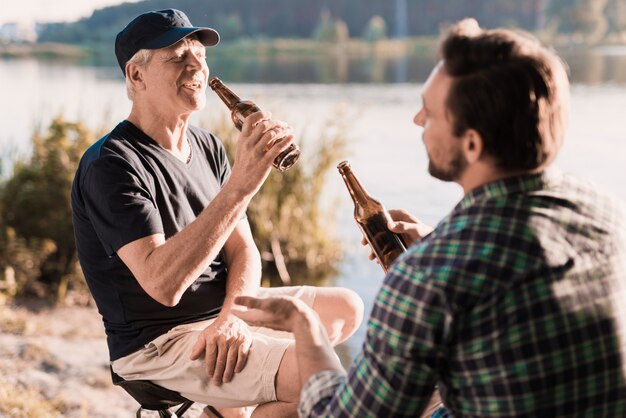 Een man in een blauw shirt drinkt bier op de rivier