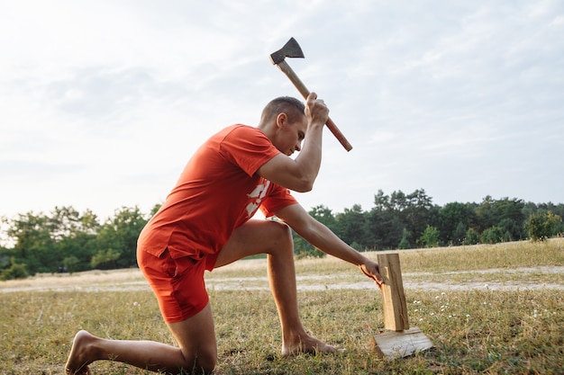 Een man in een campingstad hakt brandhout met een bijl voor een barbecue