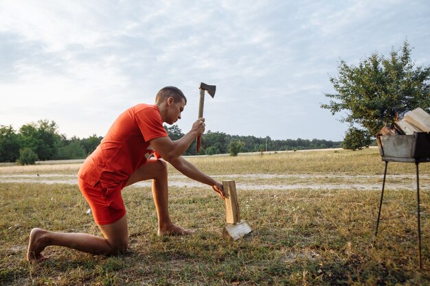 Een man in een campingstad hakt brandhout met een bijl voor een barbecue