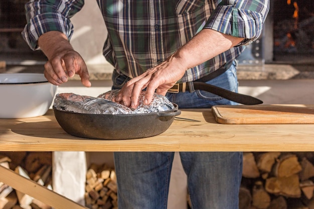 Een man in een geruit overhemd kookt varkensvlees Backstage koken traditionele Europese gerechten in brand in de oven Het concept van het kookproces Heet recept Bevroren beweging