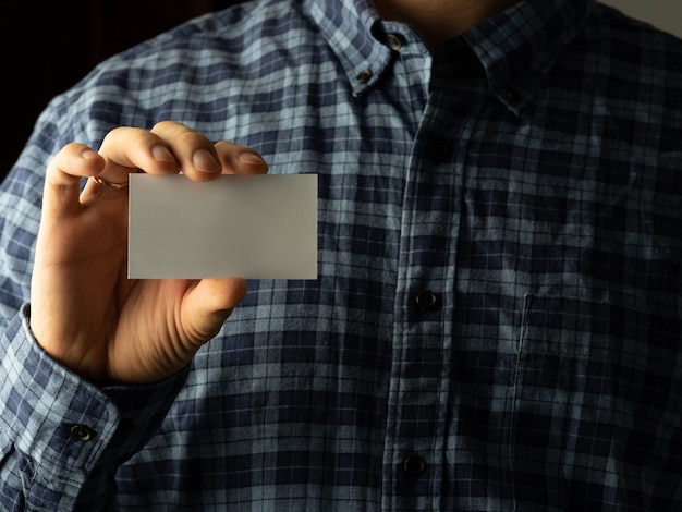 Een man in een geruit overhemd steekt een visitekaartje in de zak van zijn overhemd. kopieer ruimte